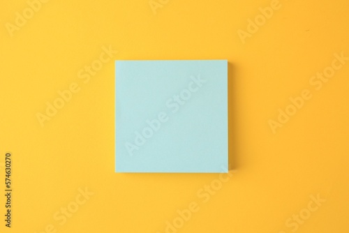Blank paper note on orange background, top view
