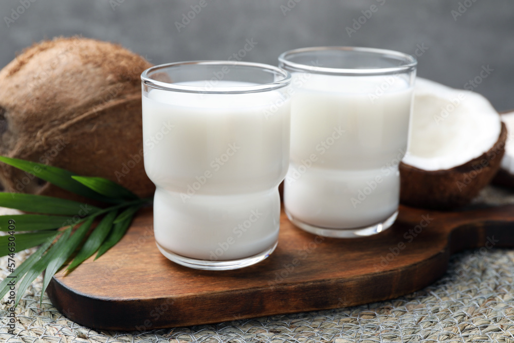 Glasses of delicious coconut milk, palm leaf and coconuts on table Glasses of delicious coconut milk, palm leaf and coconuts on table