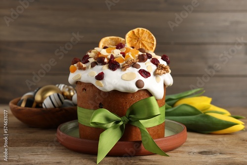 Tasty Easter cake with dried fruits, flowers and decorated eggs on wooden table