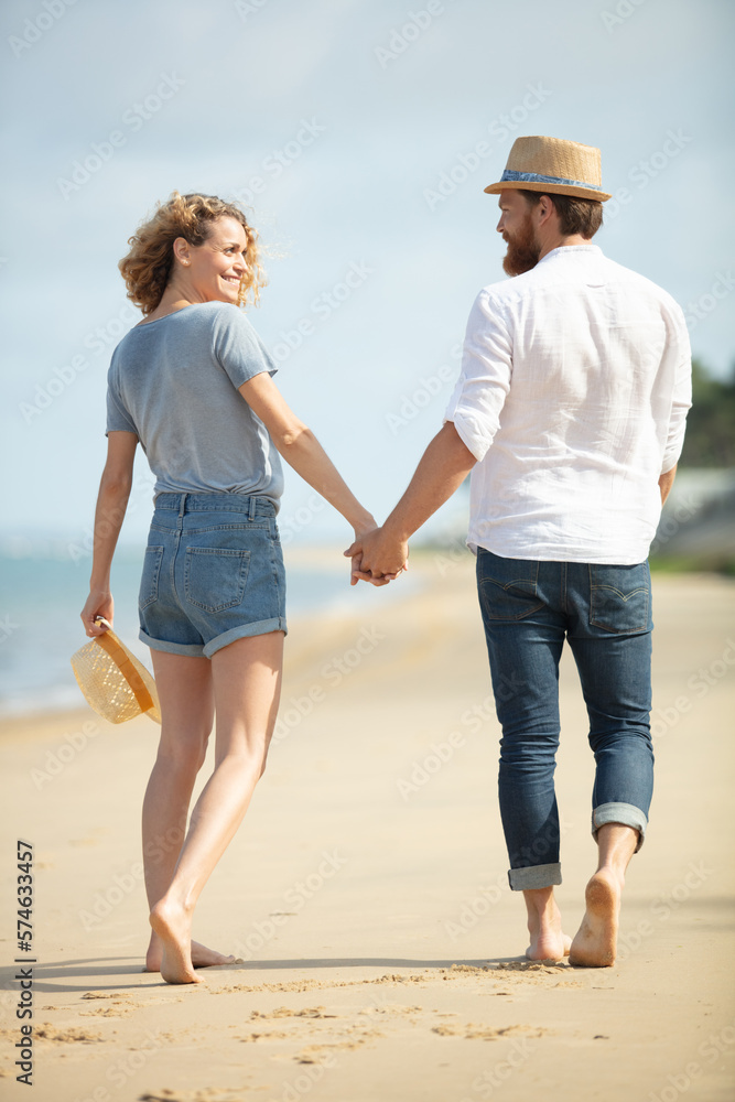 happy young couple holding hands on the beach happy young couple holding hands on the beach