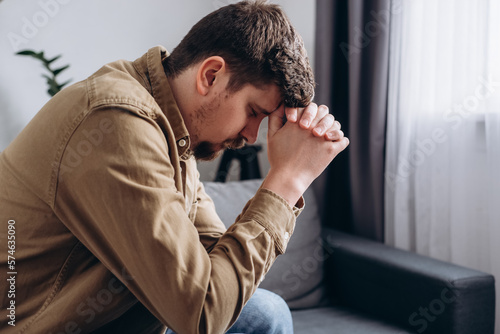 Photography Close up of anxious sad young man 30s sitting on couch at home, worrying about difficult life situation, health problems or relationship troubles, lost in negative thoughts