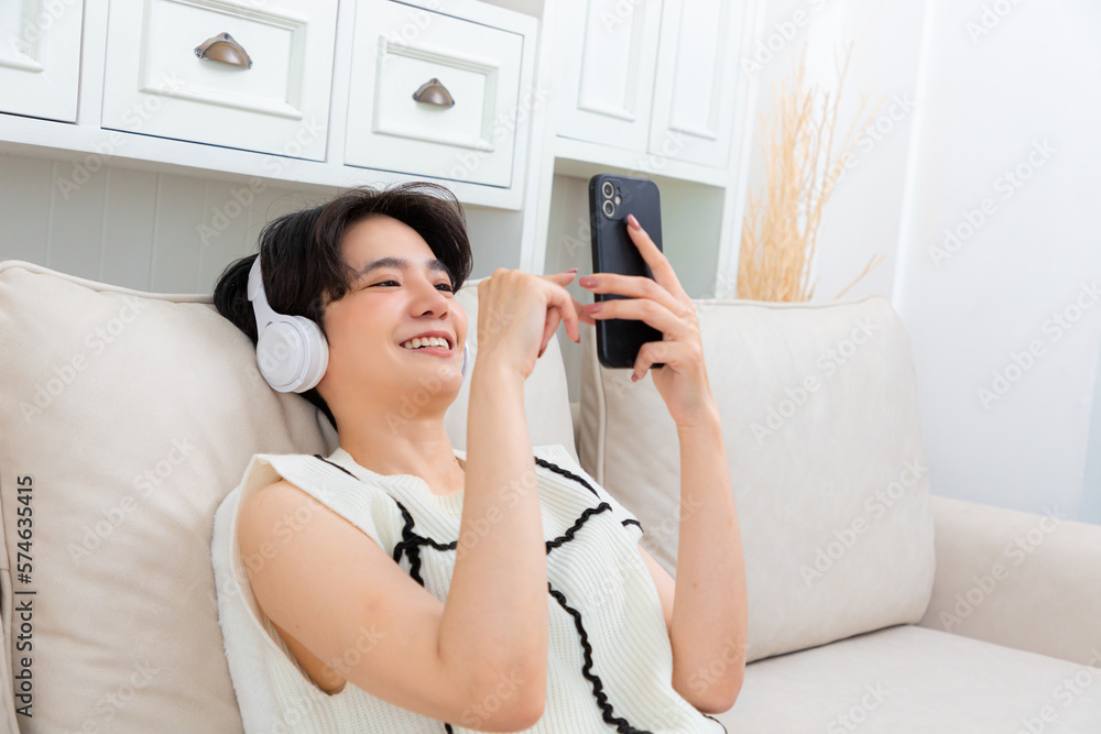 Photo of pretty lady with telephone in hands turning on cool modern song in earflaps sitting comfy sofa. Photo of pretty lady with telephone in hands turning on cool modern song in earflaps sitting comfy sofa.