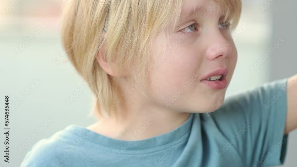 Close-up portrait of crying school-age child. Cute boy with blond hair gets angry and swears. Real emotions. Upset, offended and sad child during a tantrum. Close-up portrait of crying school-age child. Cute boy with blond hair gets angry and swears. Real emotions. Upset, offended and sad child during a tantrum.