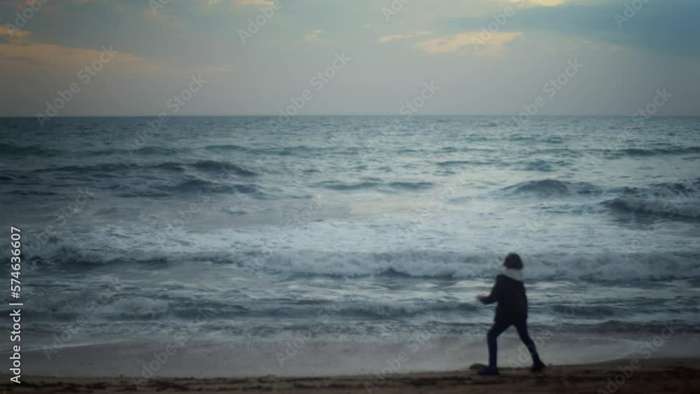 Silhouette of a teenage boy dancing alone on the beach at dusk moving to an unseen beat with a carefree energy, with the ocean in the background. He is slightly out of focus, adding a dreamy look Silhouette of a teenage boy dancing alone on the beach at dusk moving to an unseen beat with a carefree energy, with the ocean in the background. He is slightly out of focus, adding a dreamy look