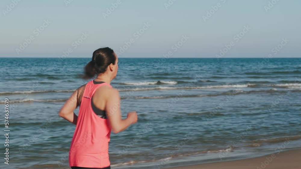 Back follow shot of running female on beach in morning. Fitness activity Back follow shot of running female on beach in morning. Fitness activity