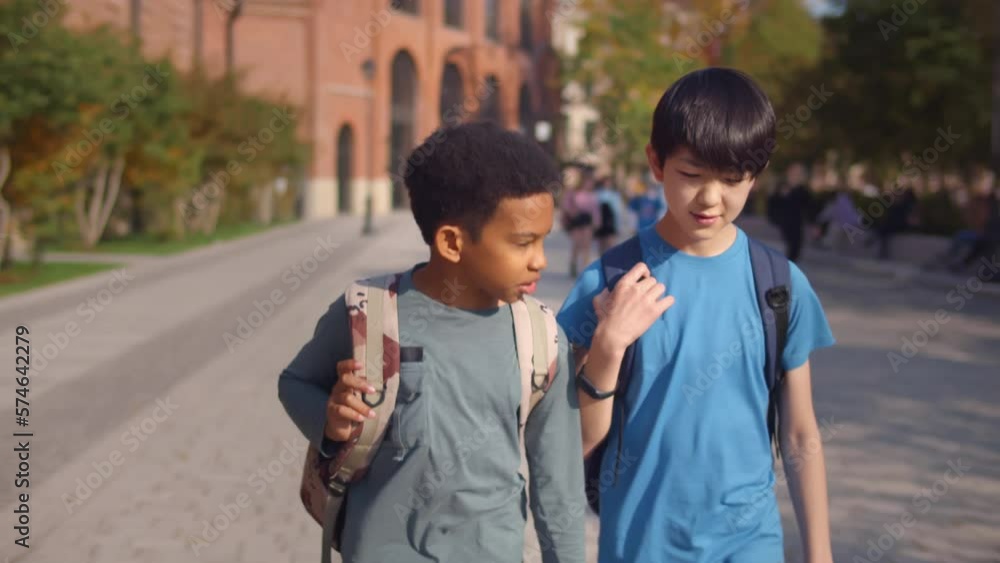 Diverse preteen boys walking in park after school lessons outdoors. Realtime Diverse preteen boys walking in park after school lessons outdoors. Realtime