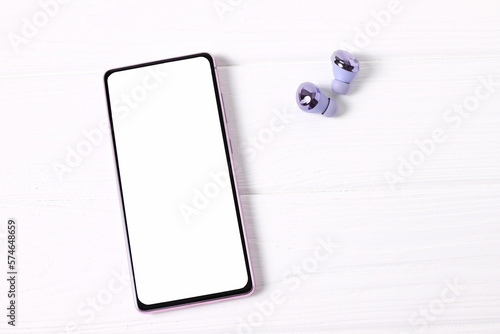 Mockup smartphone and wireless headphones on white table