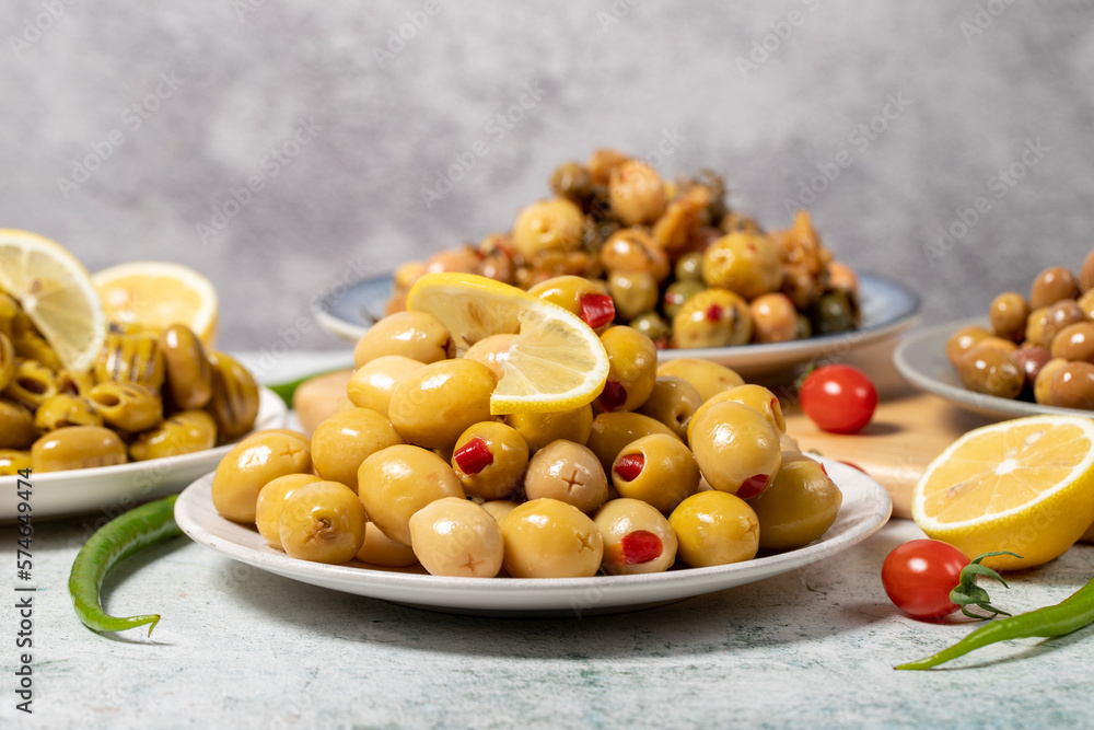 Olive varieties. Assortment of black and green olives on plate on gray background. low angle view Olive varieties. Assortment of black and green olives on plate on gray background. low angle view