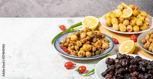 Olive varieties. Assortment of black and green olives on plate on gray background. Empty space for text. Copy space