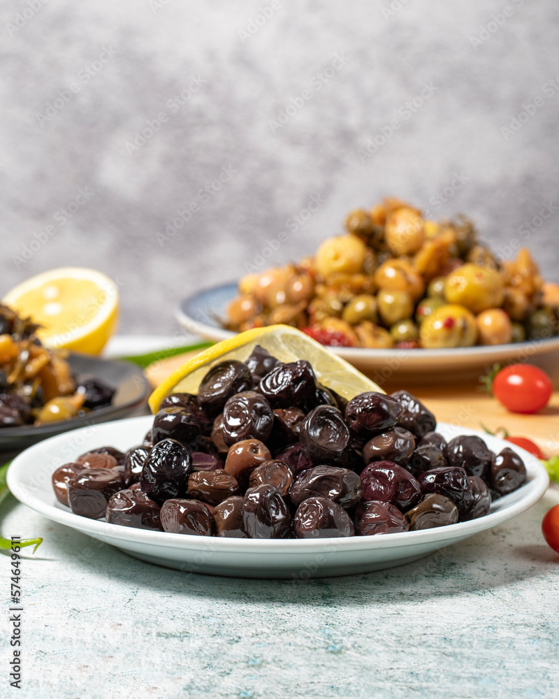 Olive varieties. Assortment of black and green olives on plate on gray background. low angle view Olive varieties. Assortment of black and green olives on plate on gray background. low angle view