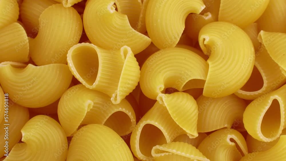 Top view of yellow uncooked pipe rigate snail shape Italian pasta circle rotation close up Top view of yellow uncooked pipe rigate snail shape Italian pasta circle rotation close up