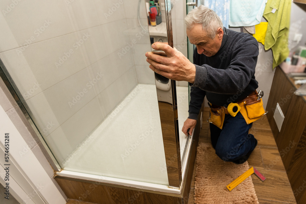 an elderly man is repairing a shower cabin