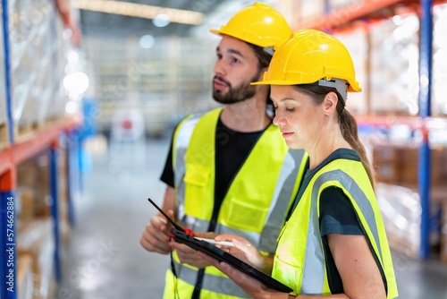 Warehouse worker standing check stock quantity of product and key information to tablet pc