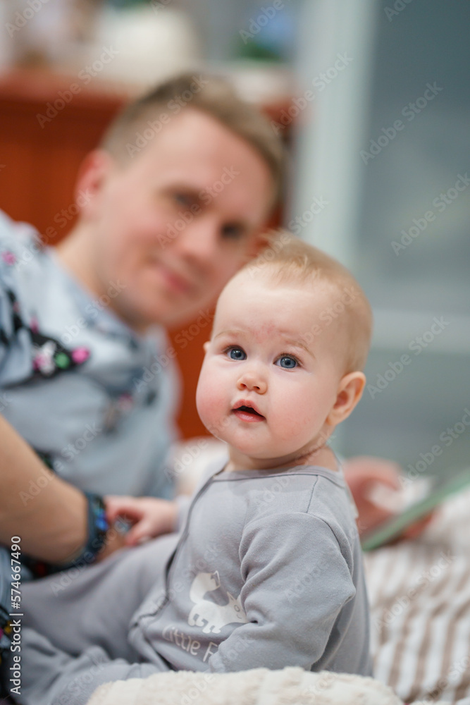 Cute little baby looks into the camera, father in the background Cute little baby looks into the camera, father in the background