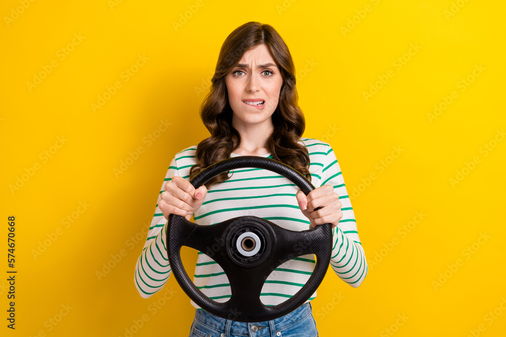 Obraz premium Photo portrait of pretty young girl bite lips nervous hold car rudder dressed stylish striped outfit isolated on yellow color background