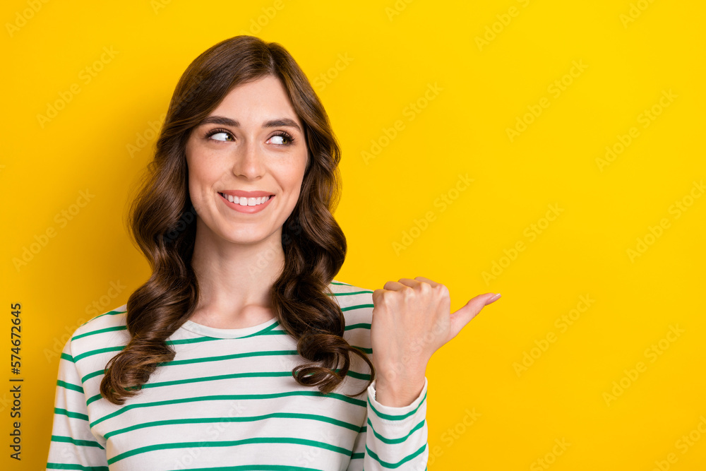 Photo of interested lovely pretty woman direct finger empty space thumb mockup useful tips discount promo code isolated on yellow color background Photo of interested lovely pretty woman direct finger empty space thumb mockup useful tips discount promo code isolated on yellow color background