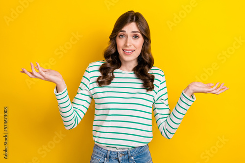 Portrait of careless clueless girl raise hands palms shrug shoulders isolated on yellow color background