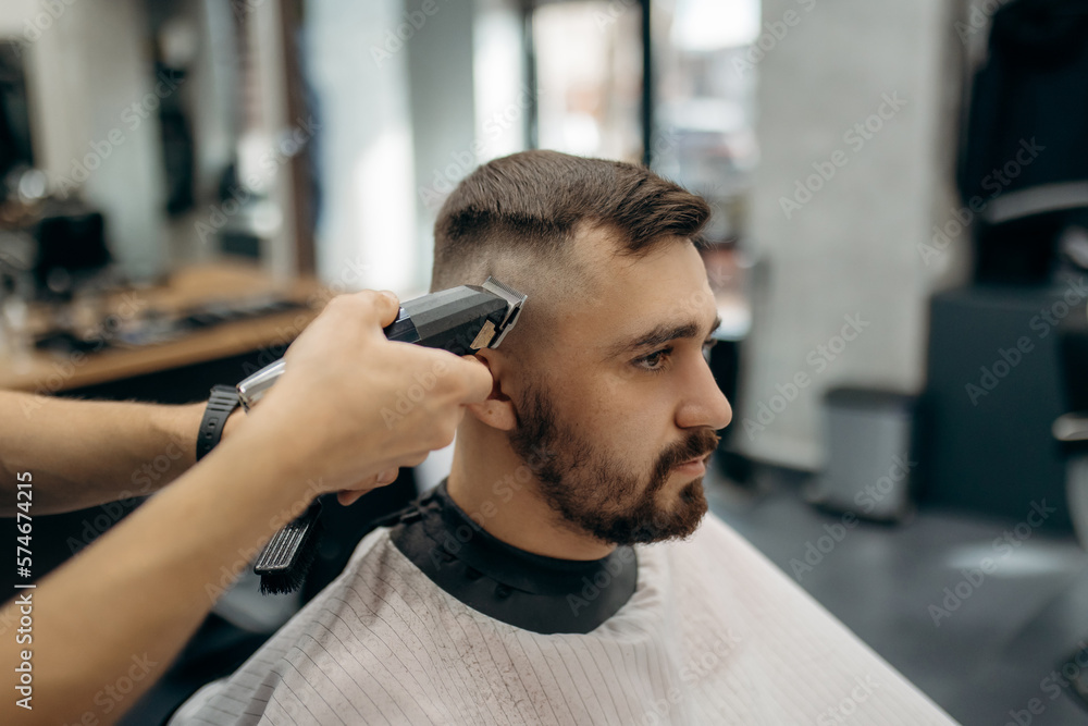 A close-up photo of a man's hair cut. A professional hairdresser cuts a man with beard in a barbershop. Men's beauty salon. A close-up photo of a man's hair cut. A professional hairdresser cuts a man with beard in a barbershop. Men's beauty salon.