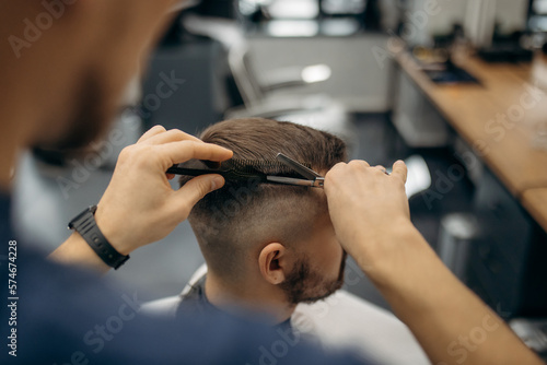 A close-up photo of a man's hair cut. A professional hairdresser cuts a man with scissors in a barbershop. Men's beauty salon.