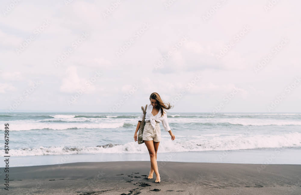 Young carefree woman walking along sandy beach