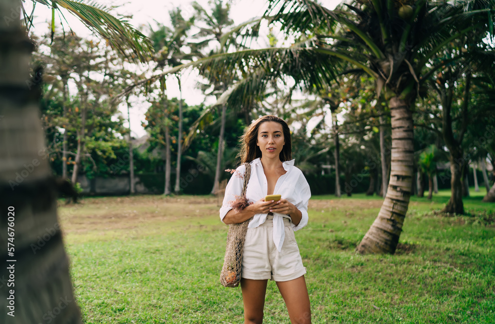 Naklejka premium Happy woman with smartphone standing in park