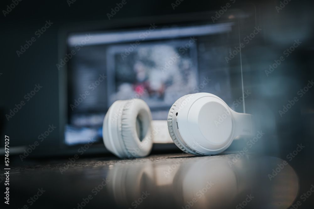 White headphones and laptop on table in dark room. White headphones and laptop on table in dark room.