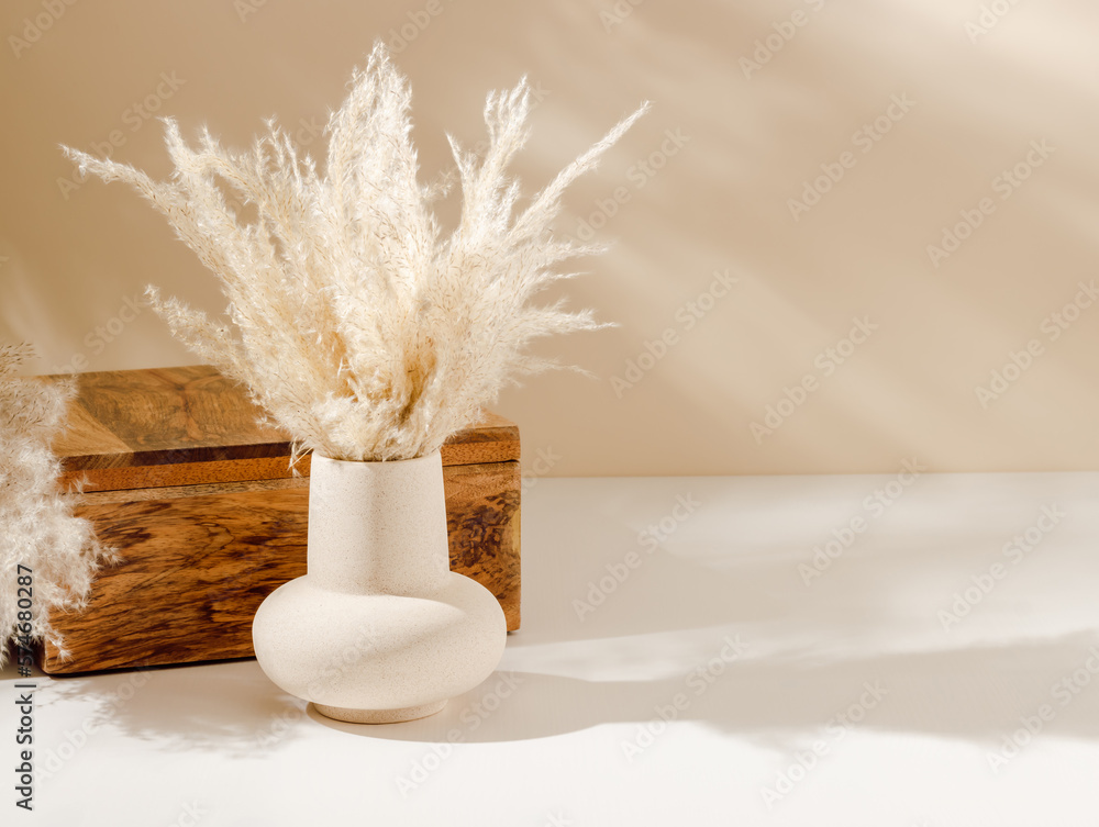 Vase with pampas grass on the table with wooden box organizer and copy space, warm shadows. Aesthetic interior, scandinavian home  decoration with natural eco friendly grass - obrazy, fototapety, plakaty 