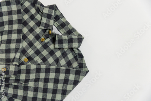 Part of a checkered children's shirt in green-gray shades with buttons for a boy or girl on a white background top view. For sale and advertising to children's clothing stores.