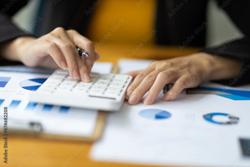 Financial accountant working on auditing and budget analysis on business reports using calculator on office desk. Financial accountant working on auditing and budget analysis on business reports using calculator on office desk.