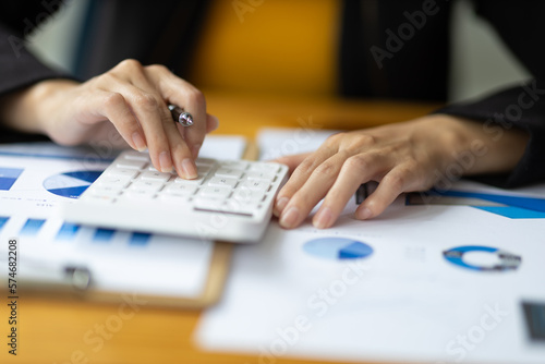 Financial accountant working on auditing and budget analysis on business reports using calculator on office desk.