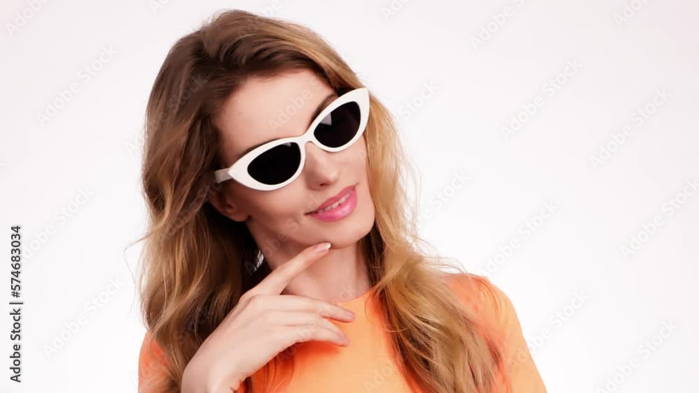 Woman smiling looking at camera. Happy positive emotional blonde girl in sunglasses. Cheerful lady smile face, beauty self-love concept. Indoors studio, pretty young lady isolated on white background Woman smiling looking at camera. Happy positive emotional blonde girl in sunglasses. Cheerful lady smile face, beauty self-love concept. Indoors studio, pretty young lady isolated on white background