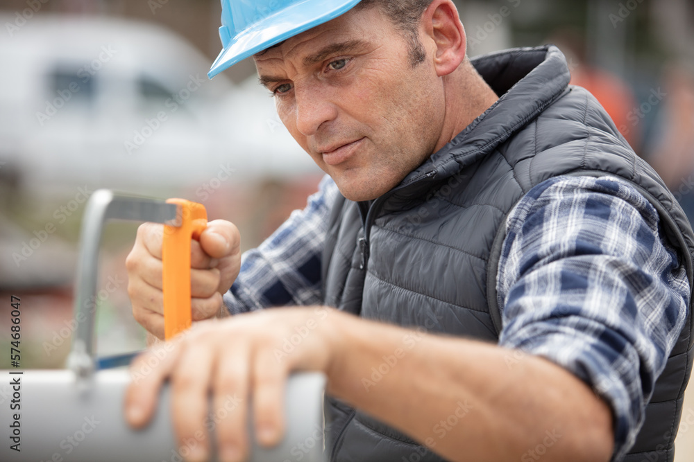 Fototapeta premium plumbing sawing plastic pipe on construction site