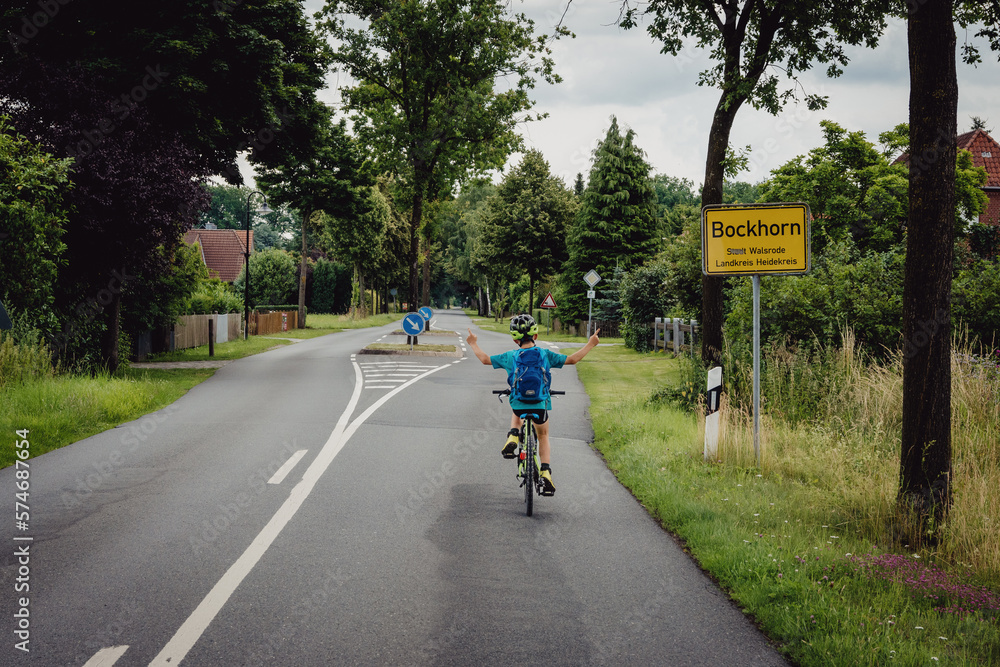 Kleiner Junge beim Ortsschild-Sprint während einer Fahrradtour, Niedersachsen, Deutschland Kleiner Junge beim Ortsschild-Sprint während einer Fahrradtour, Niedersachsen, Deutschland