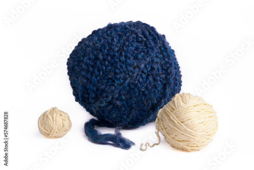 Against a pure white background, this image displays a large blue woolen thread ball alongside two small beige ones, showcasing captivating textures and colors.