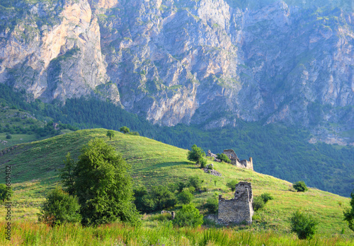 Beautiful mountain view - ruins of the ancient ingush ancestral complex Barkinhoy, green hill and barren rock at the background. Morning near Leimi village, Ingushetia, North Caucasus, Russia photo
