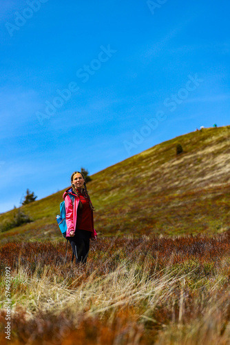 cute hiker girl with pigtails standing on the mountainous glade during spring; colorful spring in the european mountains, 