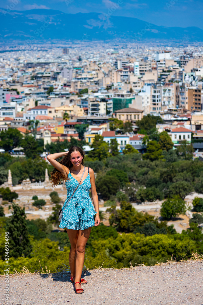 beautiful long hair tanned model standing on the hill with athens city in the backgroud; vacation in the capitol of greece, short dress woman