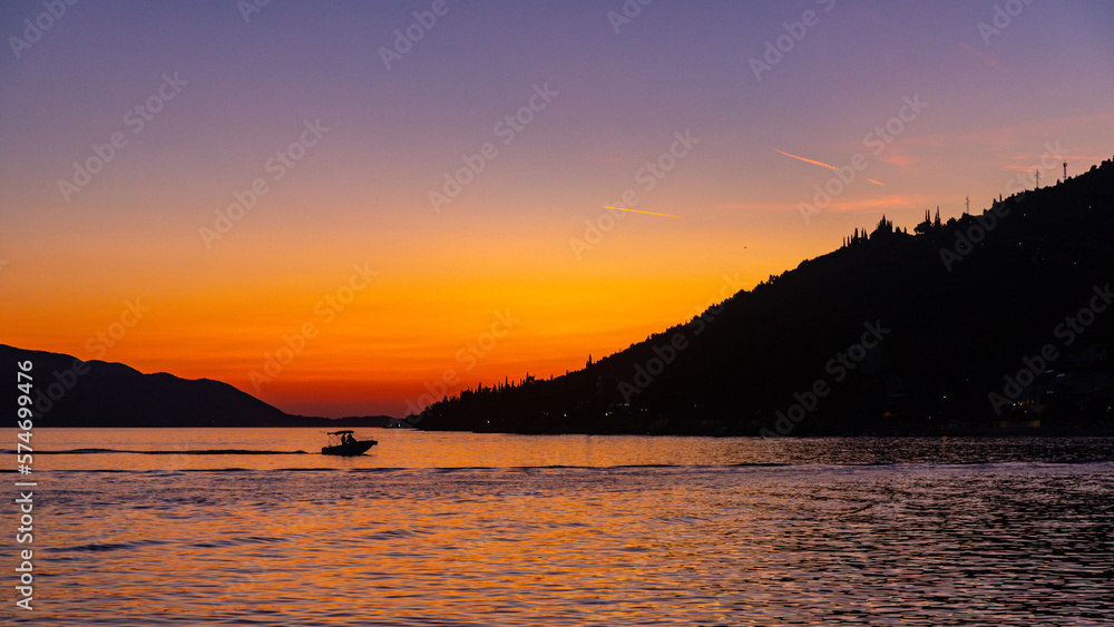 colorful sunset in orebić harbor, peljesac peninsula, croatia; dark silhouettes of yachts and boats with red sunset in the background