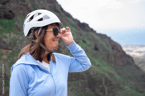 Portrait of happy senior woman hiker with helmet on the top of mountain - Smiling climbing tourist enjoying holidays and healthy lifestyle - Freedom, success sport concept