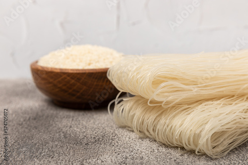 Dried raw rice noodles and rice on a light texture background.Noodles with rice flour. Funchoza. Diet food. Healthy food. Place for text. Place for copying.