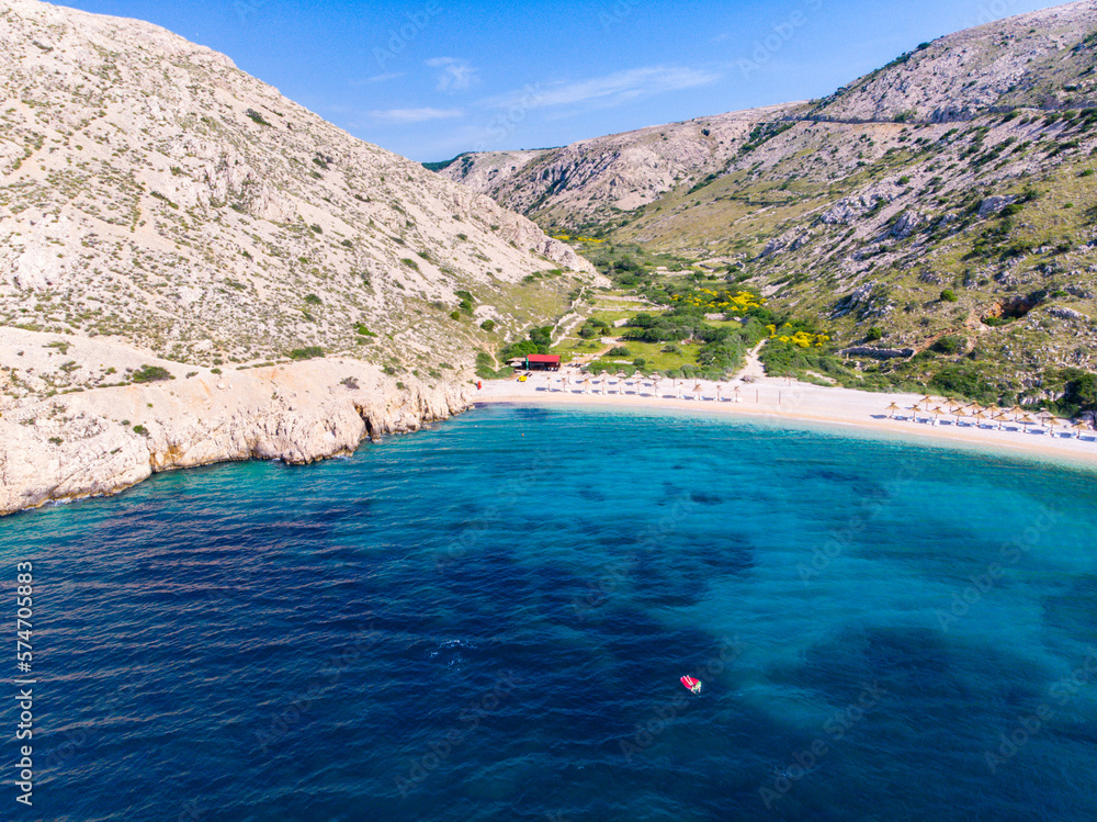aerial view of a spectacular little bay in croatia, krk island on the shore of adriatic sea; drone view of girl floating on the red mattress, relax in the mediterranean sea