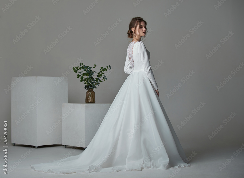 A beautiful young bride model in long lace dress in minimalist white studio interior. Wedding photography. A beautiful young bride model in long lace dress in minimalist white studio interior. Wedding photography.