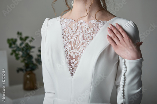 A beautiful young bride model in long lace dress in minimalist white studio interior. Wedding photography.