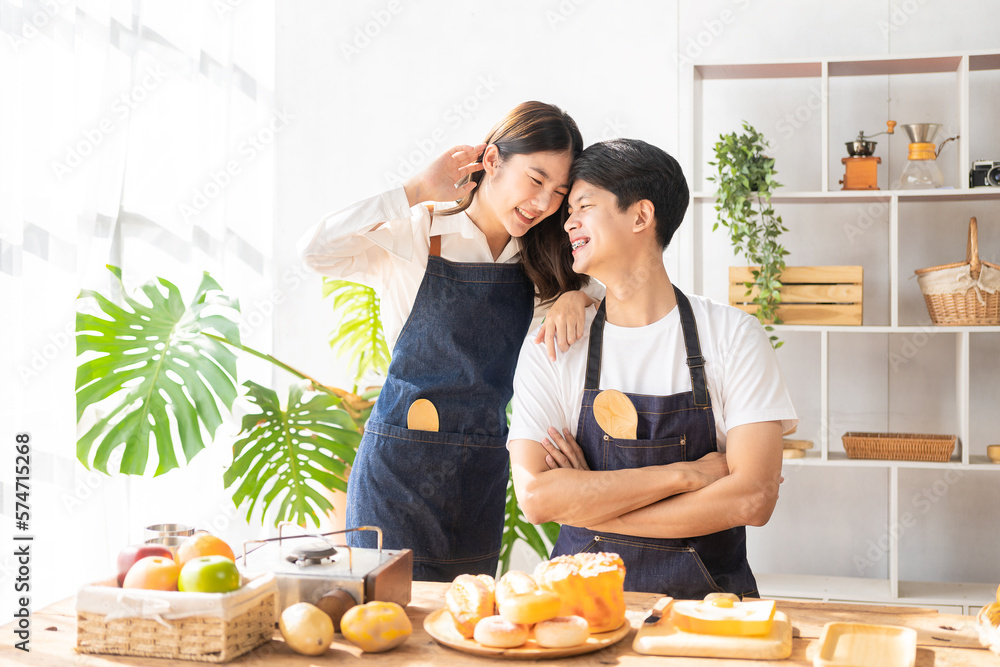Beautiful young couple preparing breakfast together in modern kitchen Kitchen man preparing food with bread and fruit in cozy kitchen in cozy house.