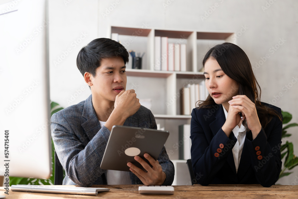 Two young Asian businessmen and a young woman use tablets to work together on business plans in the office. Businessman working on concept presentation, startup project, analyzing, planning. Two young Asian businessmen and a young woman use tablets to work together on business plans in the office. Businessman working on concept presentation, startup project, analyzing, planning.