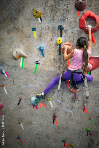 Young asian girl indoor rock climbing
