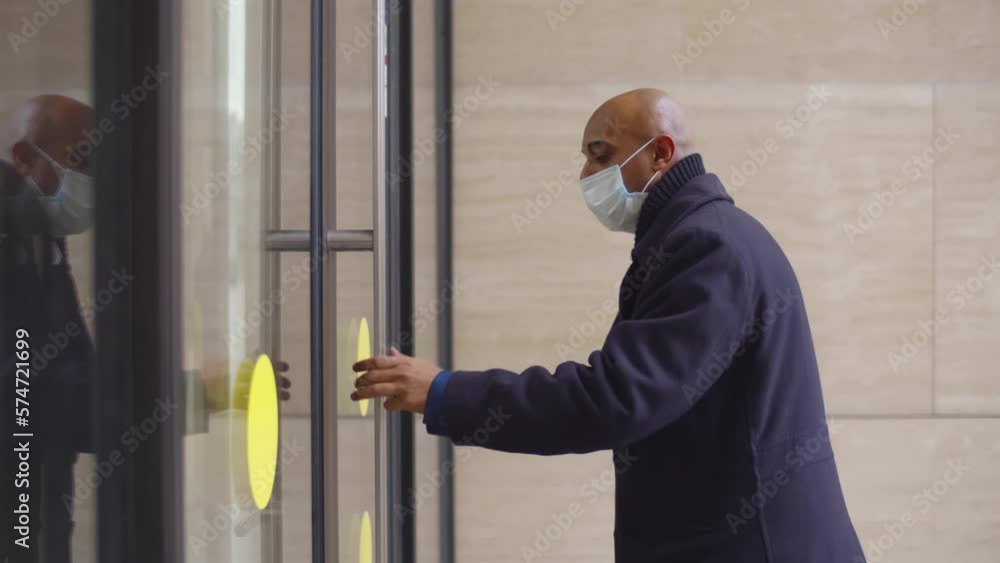 Mature businessman put on safety mask and enter business center. Realtime Mature businessman put on safety mask and enter business center. Realtime