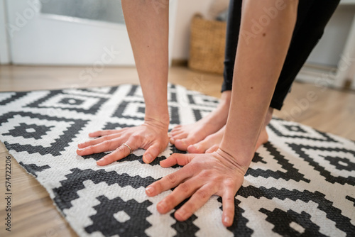 Close up on bare foot feet and hands of unknown caucasian woman stand in her apartment on the modern floor copy space yoga and stretching healthy lifestyle self care inner balance concept