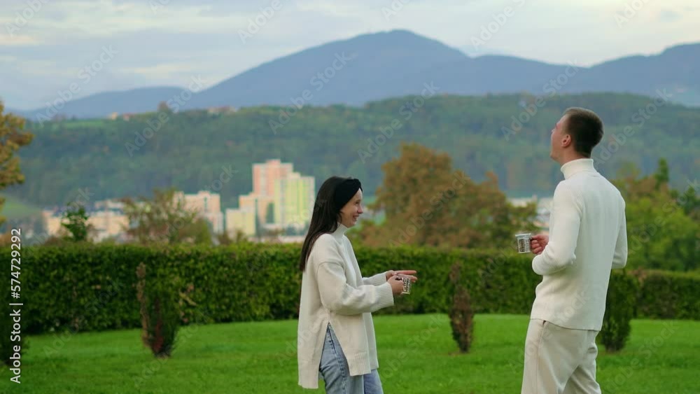 Young People Couple in white clothes Stay Communicate, drink tea, mountains background Young People Couple in white clothes Stay Communicate, drink tea, mountains background