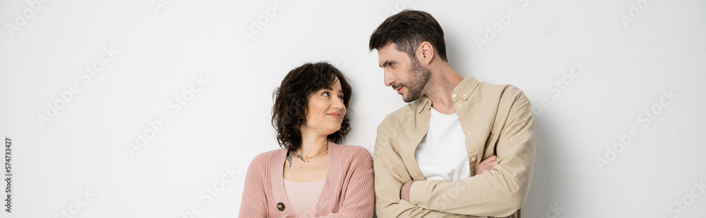 Bearded man crossing arms and looking at wife on white background, banner. Bearded man crossing arms and looking at wife on white background, banner.